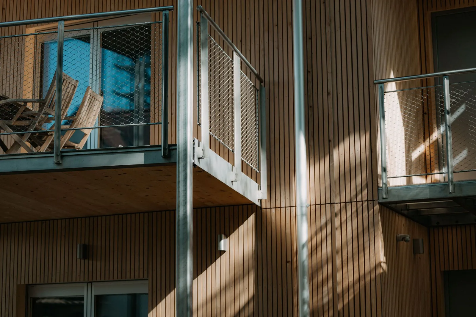 Mehrfamilienhaus mit vertikaler Holzlattung und Stahlbalkonen.